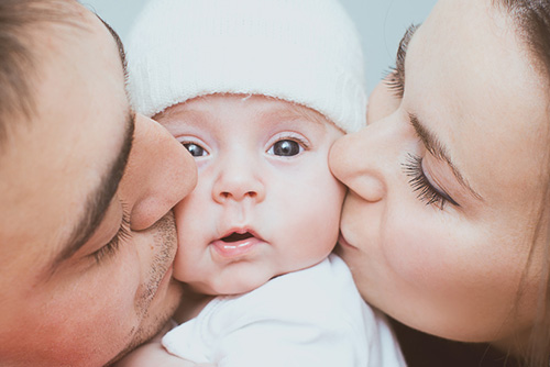 Mom & Dad Kissing Baby's Cheeks