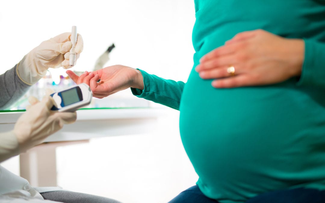 Doctor testing pregnant woman's glucose levels.