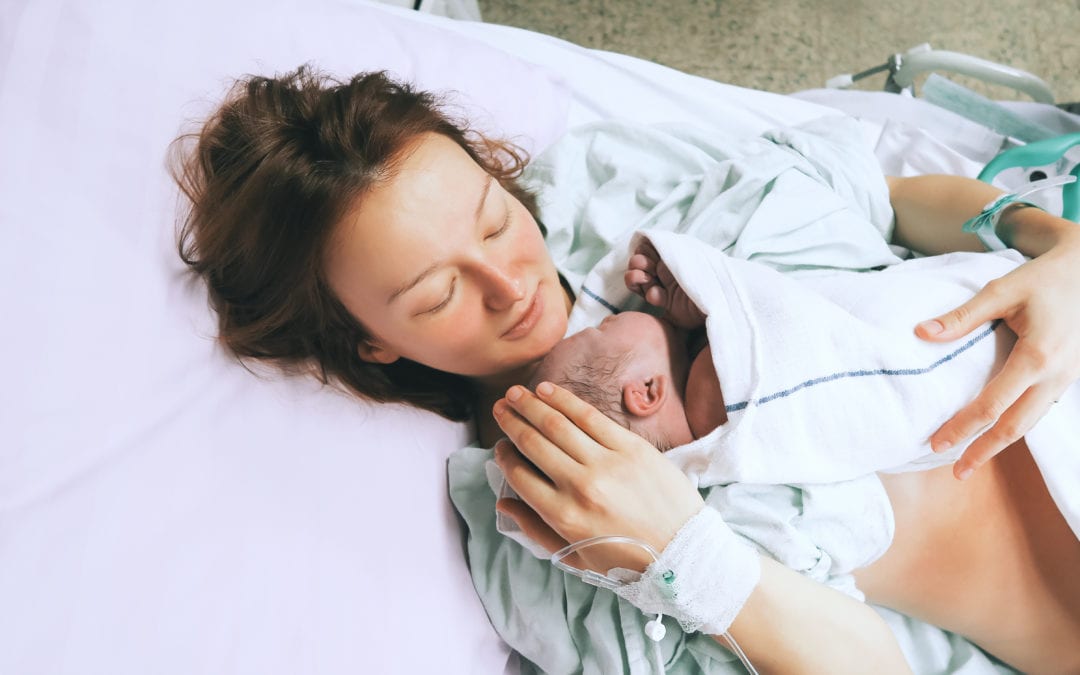 Pregnancy checklist Mom holds newborn in hospital bed.