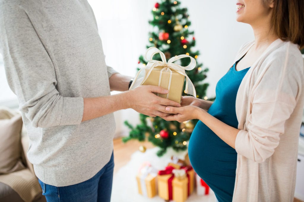 Man giving holiday gift to pregnant woman.